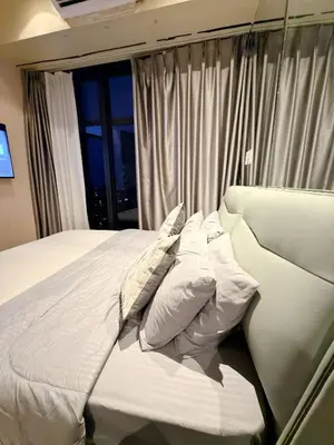 a bedroom with a white bed with pillows and a window at 61F City View at Knightsbridge Makati in Manila