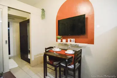 a room with a table and a television on a wall at The Soft Stay 1BR SM Jazz Makati in Manila