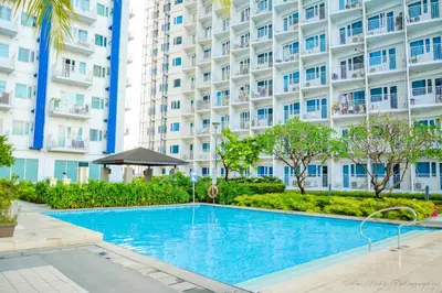 a swimming pool in front of a large building at The Soft Stay 1BR SM Jazz Makati in Manila