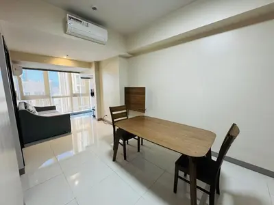 a dining room with a wooden table and chairs at Functional and Convenient stay in Eastwood City in Manila