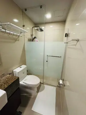 a bathroom with a toilet and a glass shower at Functional and Convenient stay in Eastwood City in Manila