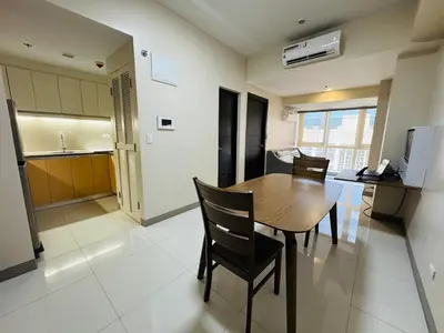 a kitchen and dining room with a wooden table and chairs at Functional and Convenient stay in Eastwood City in Manila