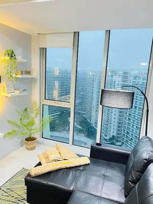a living room with a black leather couch and large windows at penthouse condo in Azure - near airport in Manila