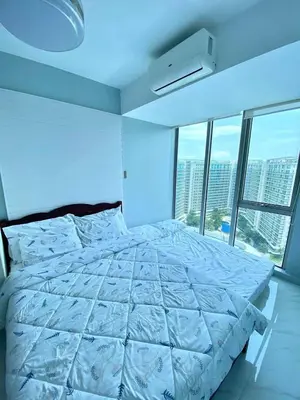 a bedroom with a white bed with a large window at penthouse condo in Azure - near airport in Manila