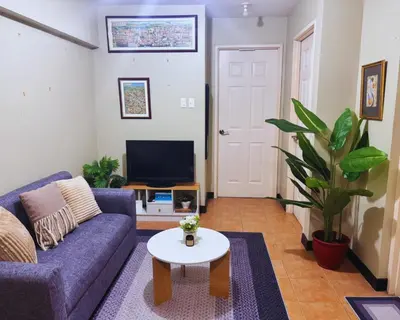 a living room with a purple couch and a tv at Modern 2BR Condo in Acacia Estate, Quiet & Green in Manila