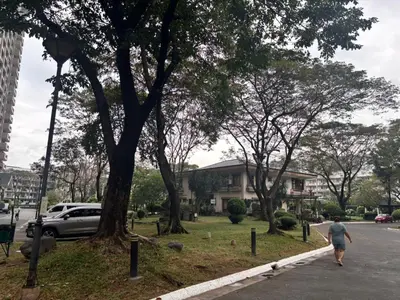 a man walking down a sidewalk next to a tree at Modern 2BR Condo in Acacia Estate, Quiet & Green in Manila
