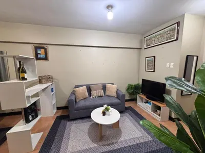a living room with a couch and a tv at Modern 2BR Condo in Acacia Estate, Quiet & Green in Manila