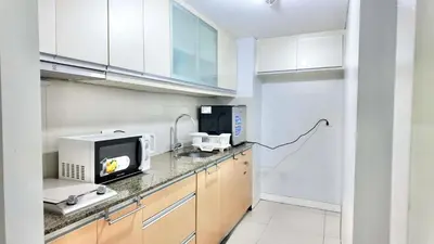 a kitchen with white cabinets and a microwave at Spacious Family Room Near NAIA Airport in Manila