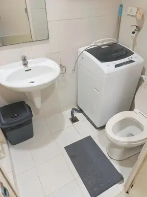 a white bathroom with a toilet and a sink at Luxx Place in Manila