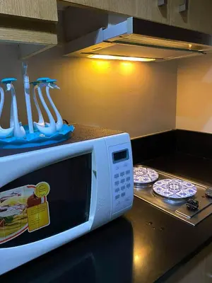 a kitchen with a microwave and plates and utensils at Queen Magzy Place in Manila