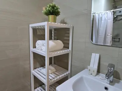 a bathroom with a white shelf next to a sink at Cozy Modern Studio Near MOA Brand New Furnishings in Manila
