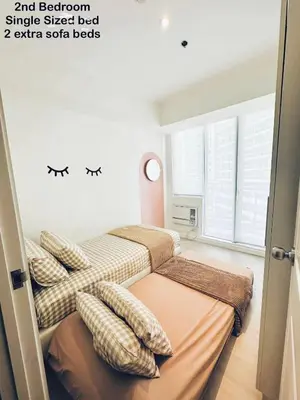 a bedroom with two beds and a window at Deluxe penthouse unit at azure - near airport in Manila