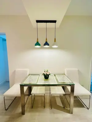 a dining room table with white chairs and two lights at Deluxe penthouse unit at azure - near airport in Manila