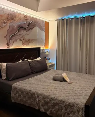 a bedroom with a bed with a large painting on the wall at Family room at azure - near airport in Manila