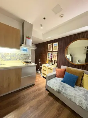 a living room with a couch and a kitchen at Family room at azure - near airport in Manila