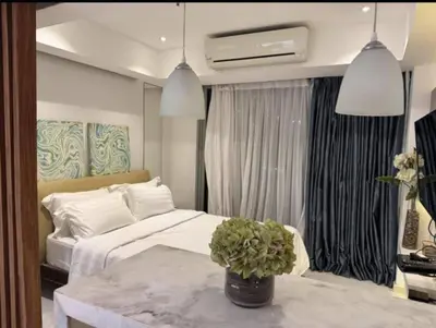 a bedroom with a bed and a table with a potted plant at Family room at azure - near airport in Manila