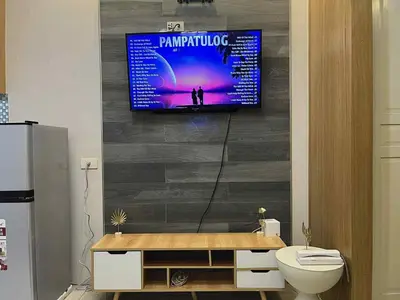 a bathroom with a tv hanging on a wall at shell residences -RJ in Manila