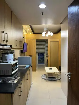 a kitchen with wooden cabinets and a table in it at shell residences -RJ in Manila