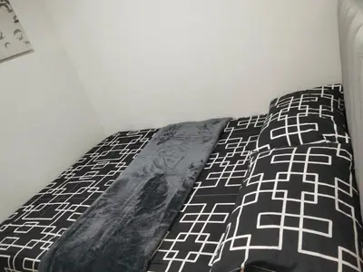 a bed with a black and white blanket on it at Condotel 1BR w balcony at MOA SMDC Shore3 T1 in Manila