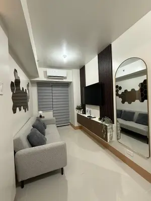 a living room with a couch and a mirror at Condotel 1BR w balcony at MOA SMDC Shore3 T1 in Manila