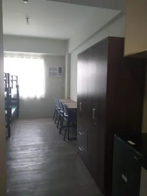 a room with a table and chairs and a wooden cabinet at MetroStay Studio Legarda in Manila