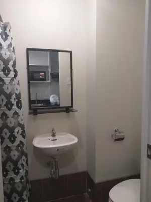 a bathroom with a sink and a mirror and a toilet at MetroStay Studio Legarda in Manila