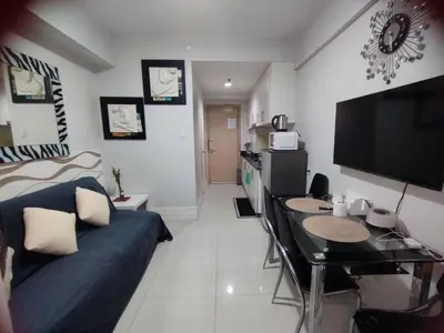 a living room with a blue couch and a table at Sea Residences Staycation by Gladys in Manila