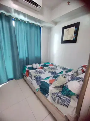 a bedroom with a bed with a blue curtain at Sea Residences Staycation by Gladys in Manila
