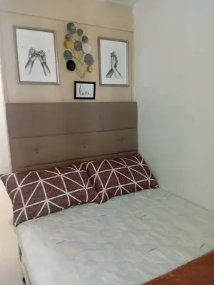 a bed in a bedroom with two pictures on the wall at Condotel Sea Residence's Place Near Moa in Manila