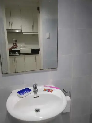 a bathroom with a white sink and a mirror at Condotel Sea Residence's Place Near Moa in Manila