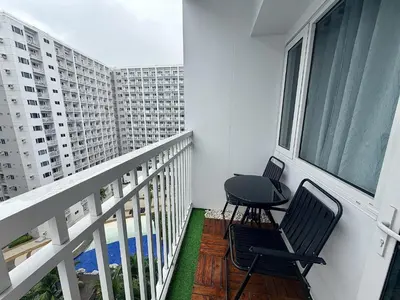 two chairs and a table on a balcony with buildings at Cozy staycation near Mall of Asia in Manila