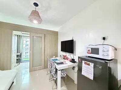 a room with a kitchen with a desk and a microwave at Cozy staycation near Mall of Asia in Manila