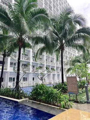 a hotel with palm trees and a swimming pool at Cozy staycation near Mall of Asia in Manila