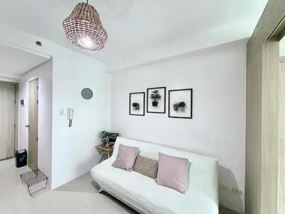a living room with a white couch with purple pillows at Cozy staycation near Mall of Asia in Manila