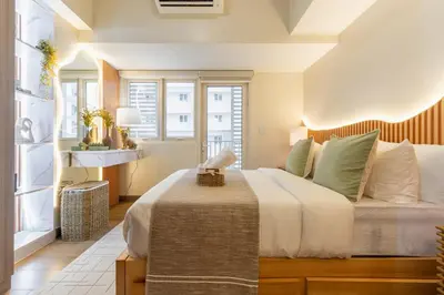 a bedroom with a large bed and windows at Cozy Modern Organic 1BR with Washer and WiFi Near BGC in Manila