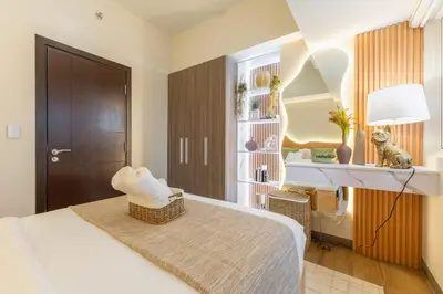 a bedroom with a bed and a desk with a lamp at Cozy Modern Organic 1BR with Washer and WiFi Near BGC in Manila