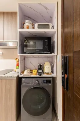 a kitchen with a washing machine and a microwave at Cozy Modern Organic 1BR with Washer and WiFi Near BGC in Manila