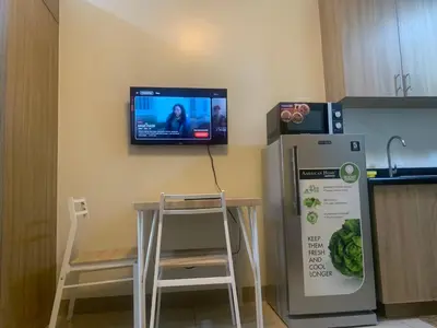 a tv on the wall of a kitchen with a refrigerator at Shore Residences by Buhay Staycation in Manila