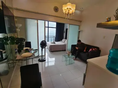a man sitting on a couch in a living room at STUDIO Type CONDO in Manila