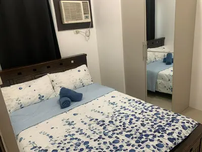 a bedroom with a bed with a blue and white comforter at Shore Residence by Buhay Staycation in Manila