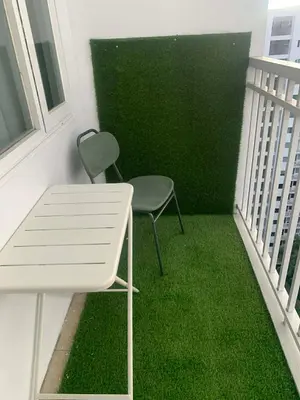 a chair and a table on a balcony with green grass at Shore Residence by Buhay Staycation in Manila