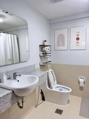 a bathroom with a sink and a toilet and a mirror at Alea Residences 1 Bedroom Condo with Pool View Balcony in Manila