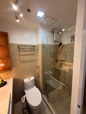 a bathroom with a toilet and a glass shower at Hotel-like flat at Bay City Haven Mall of Asia SMX in Manila