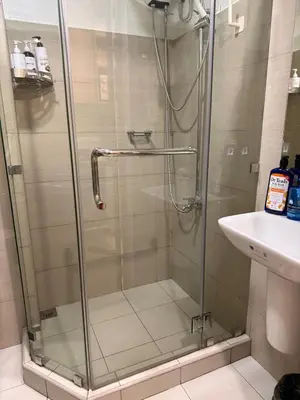 a shower with a glass door next to a sink at Manila Flat Mall of Asia SMX city view with netflix in Manila