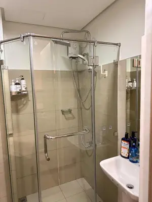a shower with a glass door next to a sink at Manila Flat Mall of Asia SMX city view with netflix in Manila