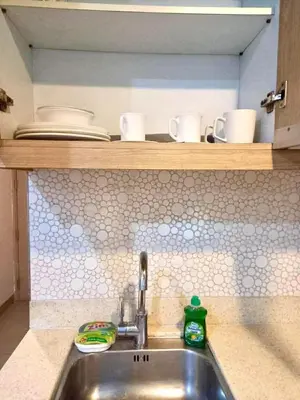 a kitchen sink with cups and dishes on a shelf at Studio in serenity - Peaceful and Calm ambiance in Manila
