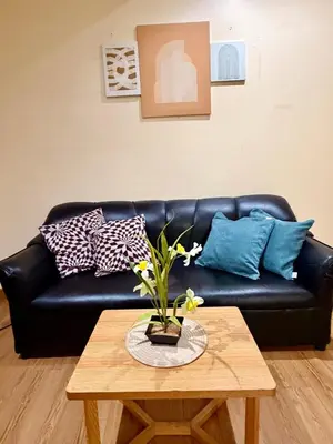 a black leather couch with pillows and a table at SYM staycation at Azure in Manila
