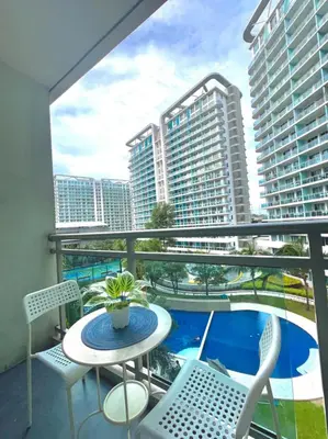 a balcony with a table and chairs and a pool at SYM staycation at Azure in Manila