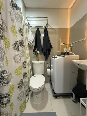 a bathroom with a toilet and a sink and a shower curtain at Modern apartment with balcony and Pool View in Manila