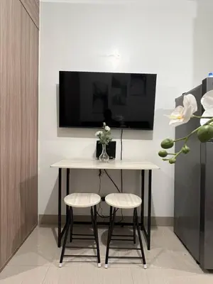 a table and two stools in a room with a tv at Modern apartment with balcony and Pool View in Manila